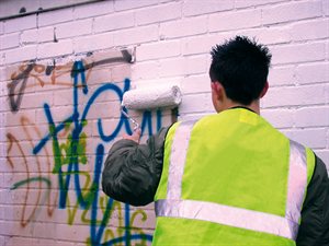 council worker removing graffiti from a wall