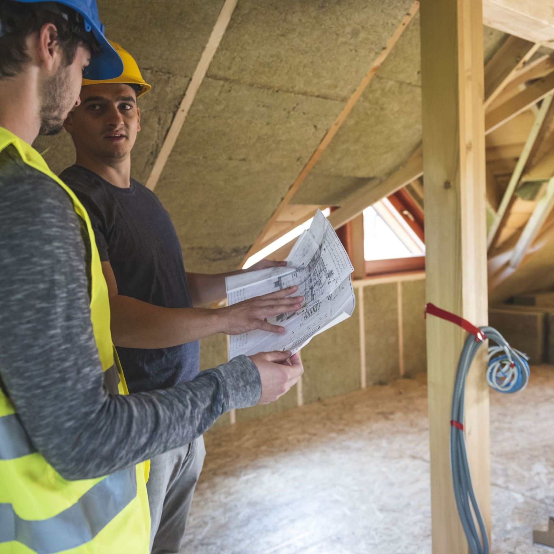 Building site workers assessing paper plans in a roof space