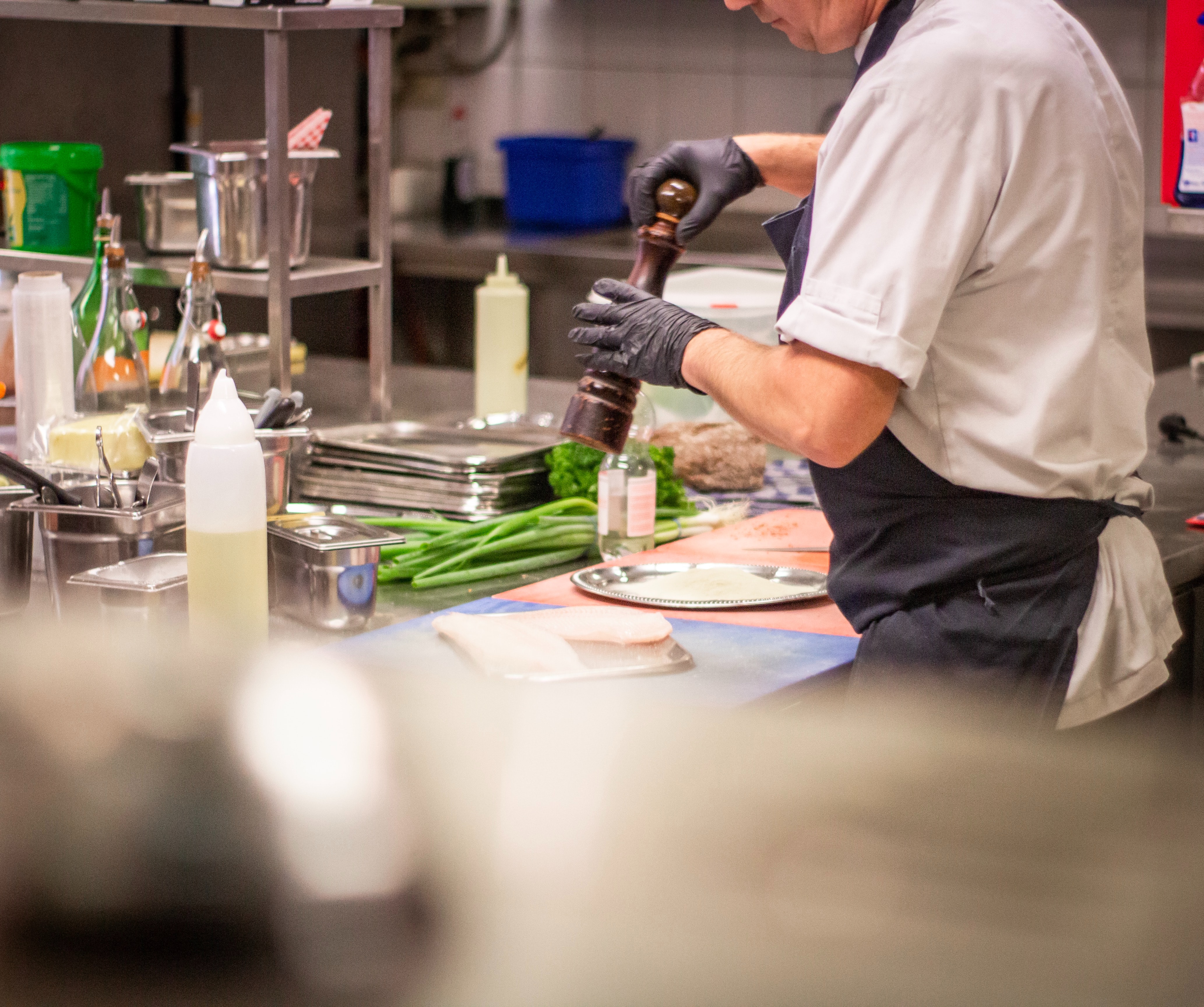 Chef seasoning food in a food business kitchen.