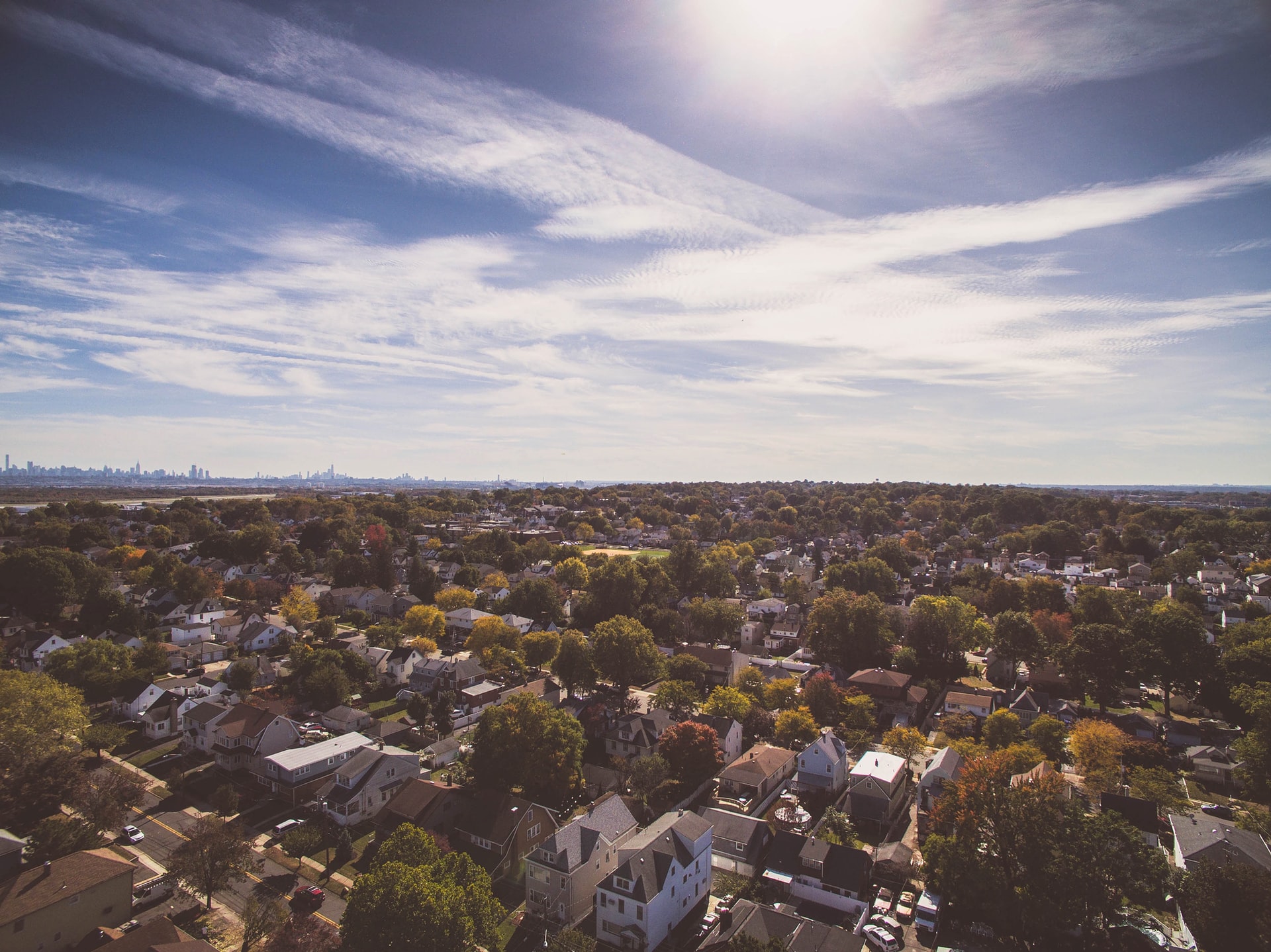 Aerial view of a residential area with houses and roads and a bright sky