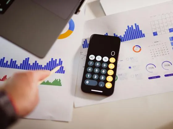 A selections of graphs with a laptop and iPhone resting on top of the papers.