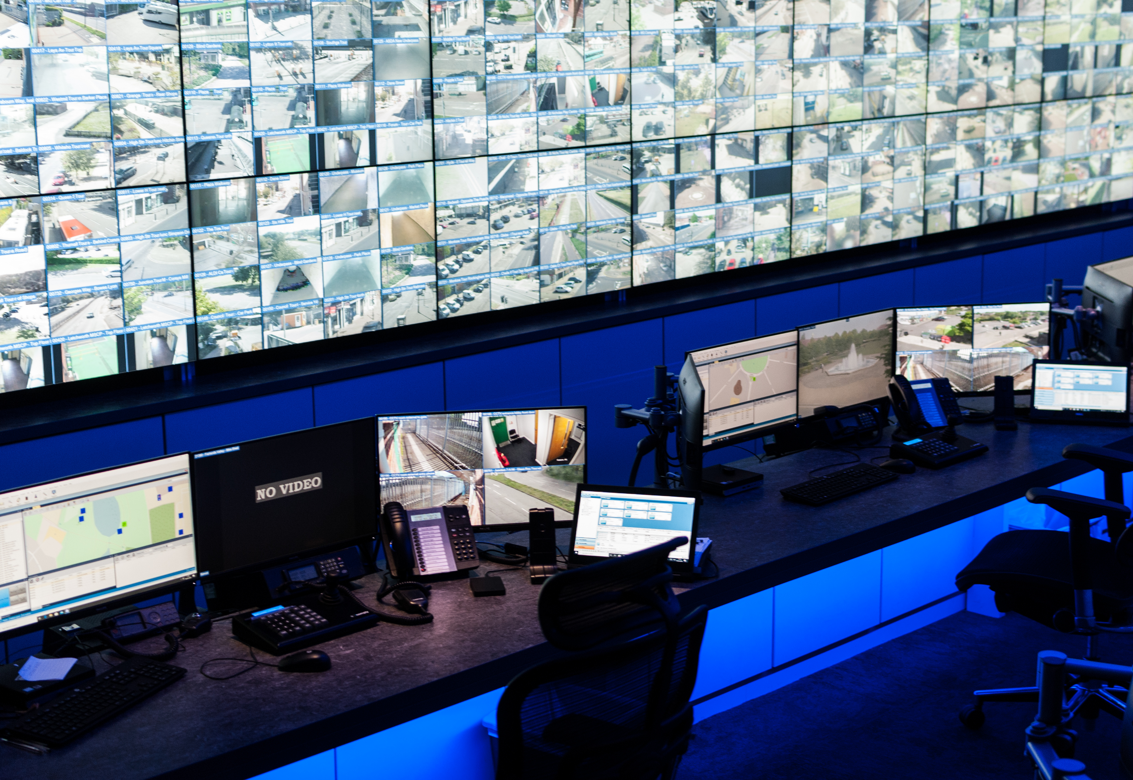 A wall of monitors in the CCTV Control Room with desks facing the wall.