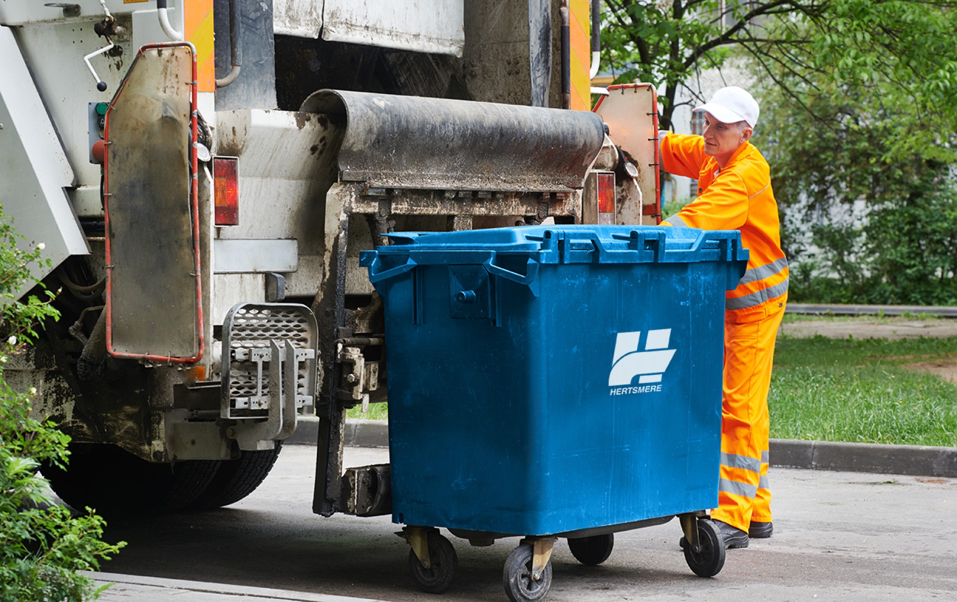Commercial waste bin being loaded onto a truck by an employee