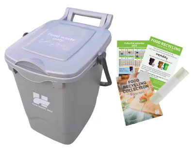 Silver food waste bin with roll of liners, calendar and service guide leaflet.