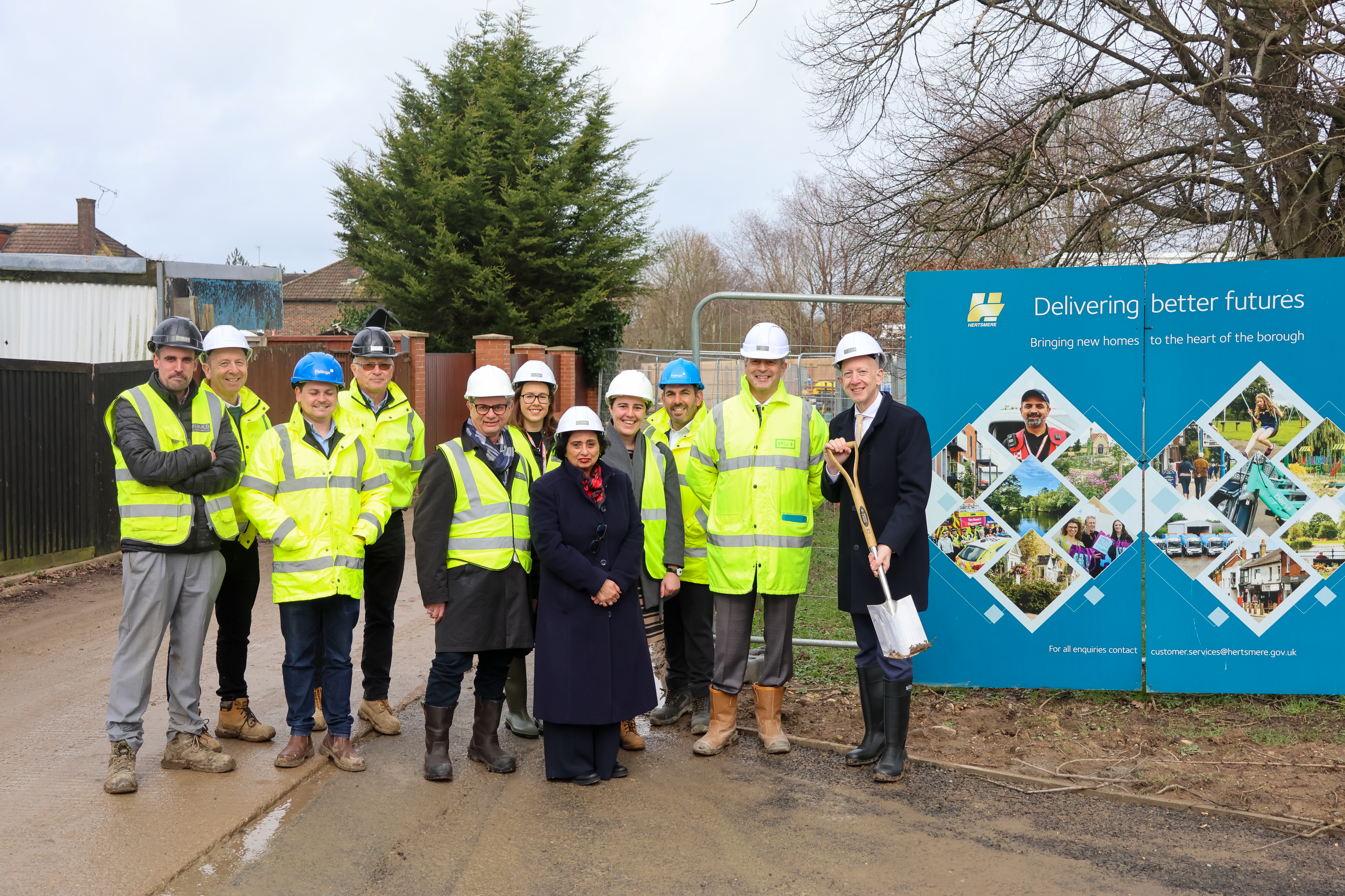 Group in high visibility vests assembled outside building site.