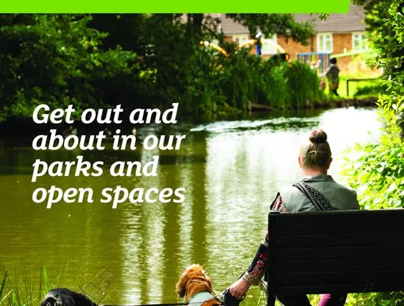The front cover of Hertsmere News featuring a lady sitting on a park bench with her two dogs on a lead.