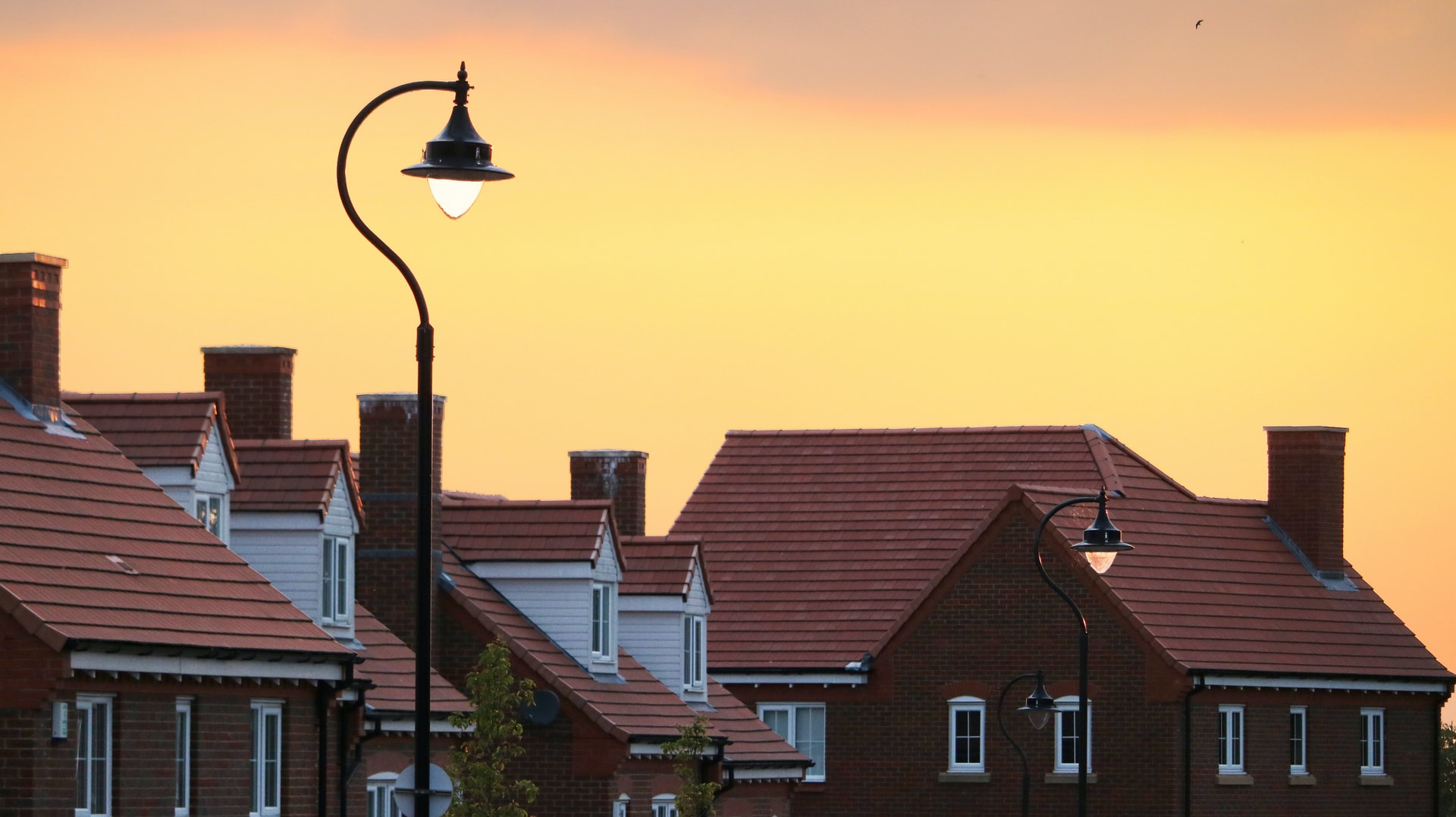 Rooftops of houses and streetlight on a sunset background