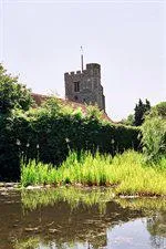 Exterior of Bushey church with lake and grass in front of building