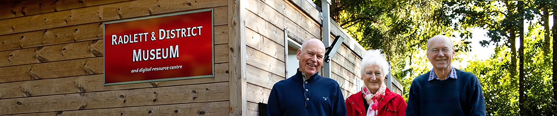 Exterior of the Museum. Three volunteers smile at the camera.