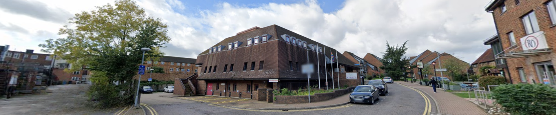 The exterior building of Wyllyotts Centre in Potters Bar with cars parked alongside the road. 