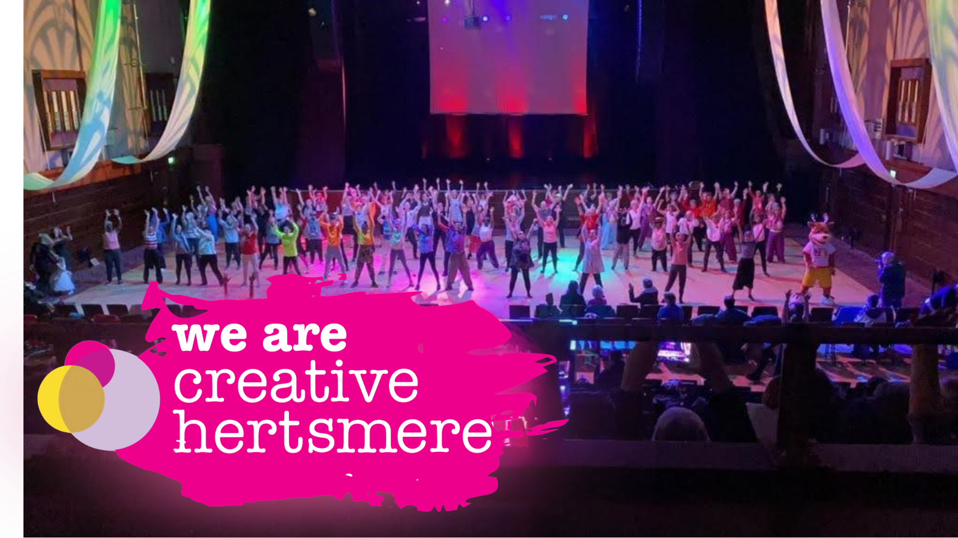Performers on a stage with the words we are creative Hertsmere in front. 